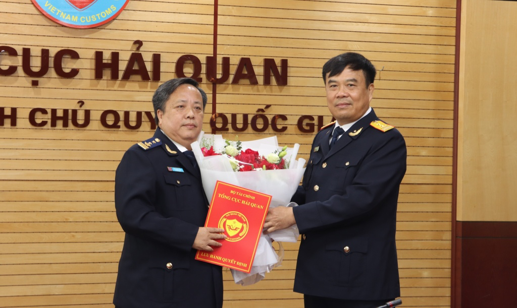 Tổng cục trưởng Tổng cục Hải quan Nguyễn Văn Thọ (bên phải) trao quyết định, tặng hoa chúc mừng ông Vũ Quang Toàn.