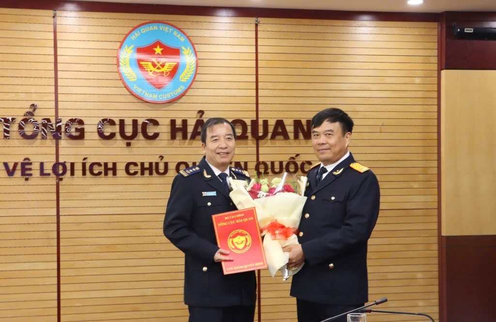 Tổng cục trưởng Tổng cục Hải quan Nguyễn Văn Thọ (bên phải) trao quyết định, tặng hoa chúc mừng ông Nguyễn Hùng Anh. 