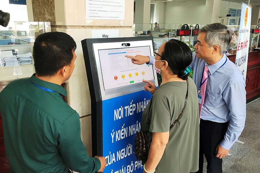 Lãnh đạo Cục Thuế TP. Hồ Chí Minh hướng dẫn người dân sử dụng máy góp ý công chức thuế trong giải quyết thủ tục thuế. Ảnh Đỗ Doãn