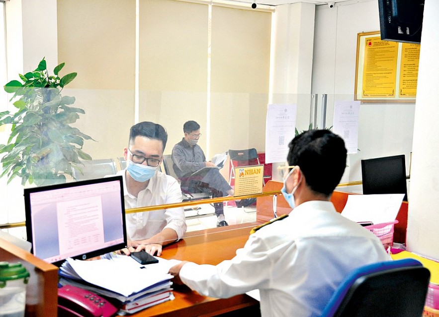 Cán bộ cục thuế Hà Nội hướng dẫn doanh nghiệp làm thủ tục thuế.    Ảnh: Nhật Minh