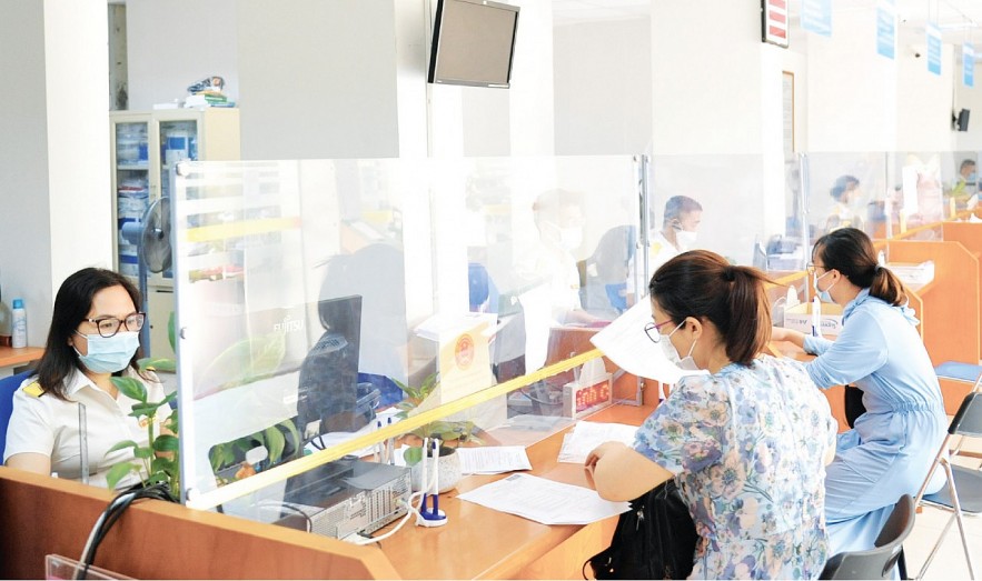 Hỗ trợ người dân làm thủ tục hành chính thuế tại bộ phận “một cửa” Cục Thuế TP. Hà Nội. Ảnh: Mai Lan