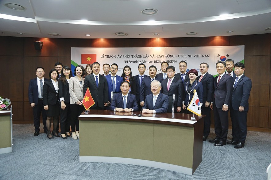 Chủ tịch Ủy ban Chứng khoán Nhà nước Trần Văn Dũng (ngồi bên trái) tại lễ trao giấy phép thành lập công ty chứng khoán NH Việt Nam. 		         Ảnh: MAI AN