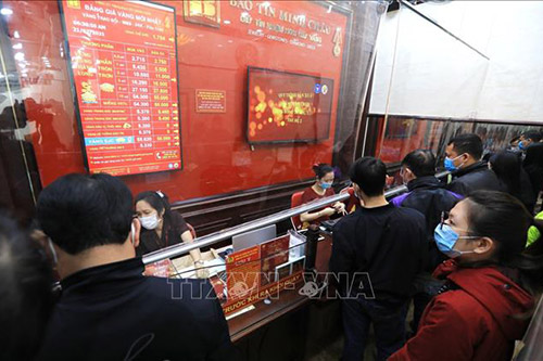 Người dân theo dõi bảng giá vàng tại cửa hàng của Công ty vàng bạc đá quý Bảo Tín Minh Châu